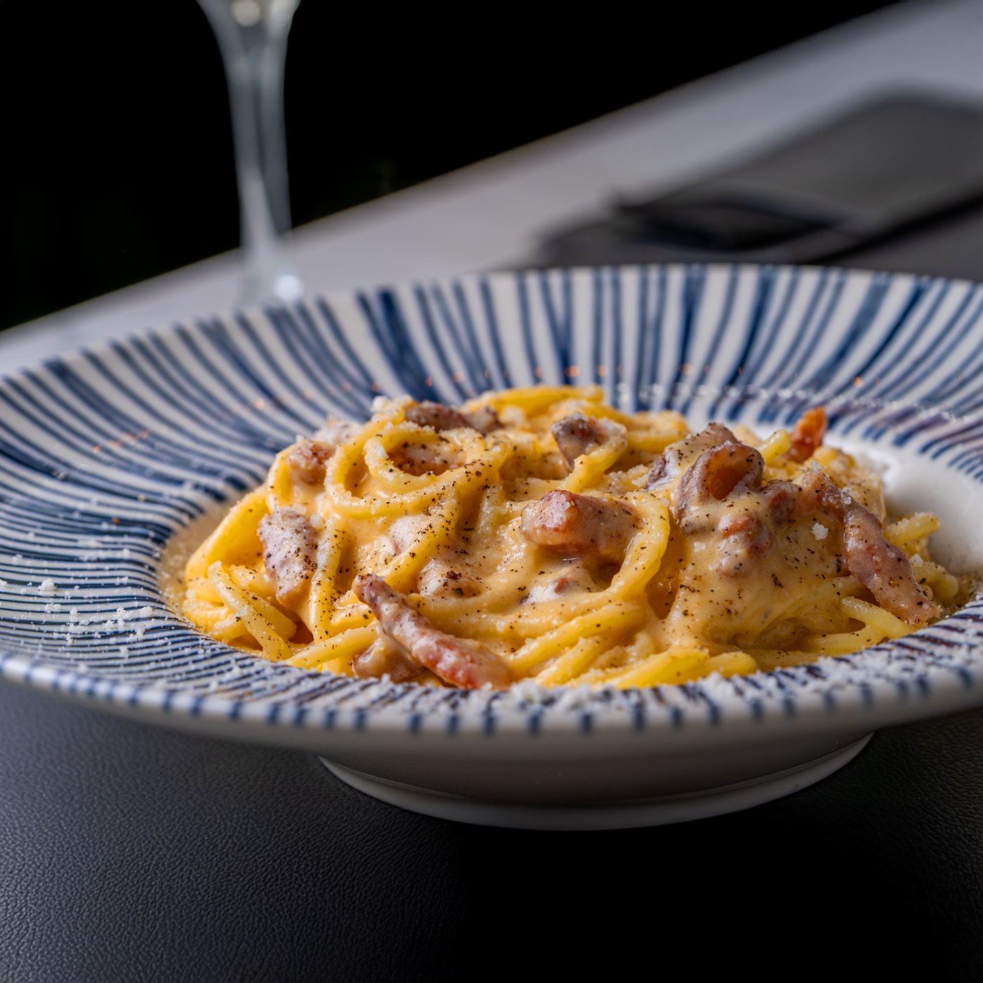 Spaghetti alla carbonara in un piatto a righe blu.